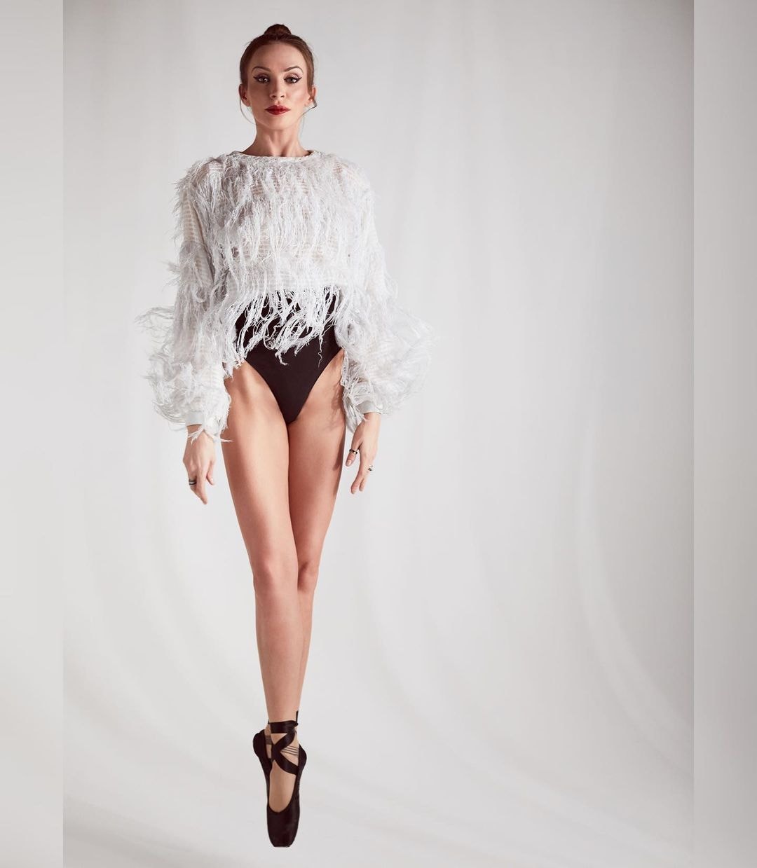 Ballet dancer on pointe — red lip, feather top, editorial beauty